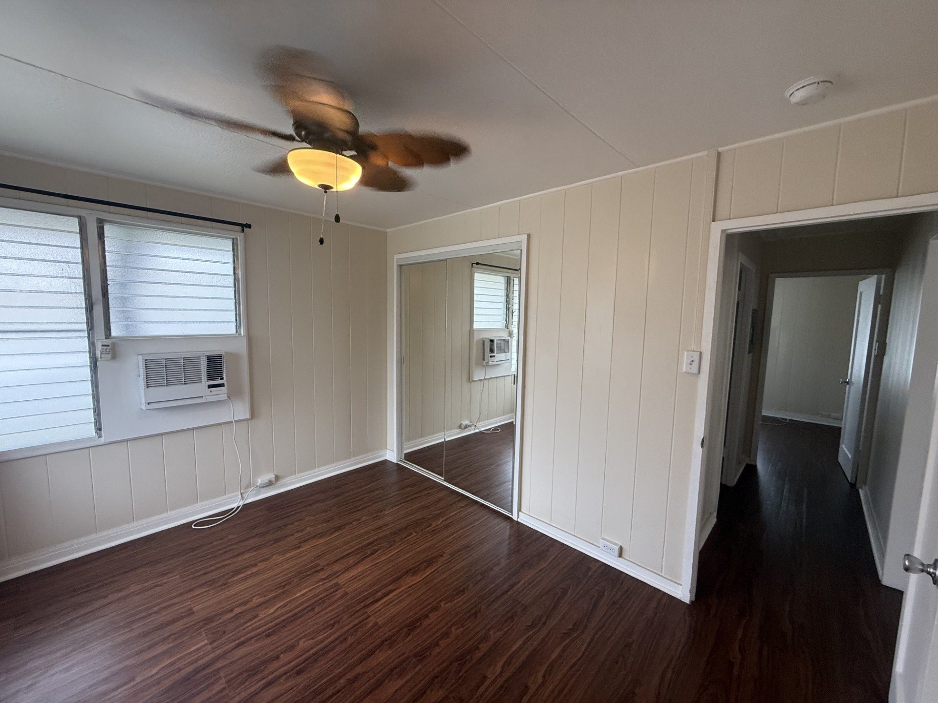 A room with a ceiling fan and wooden floors.